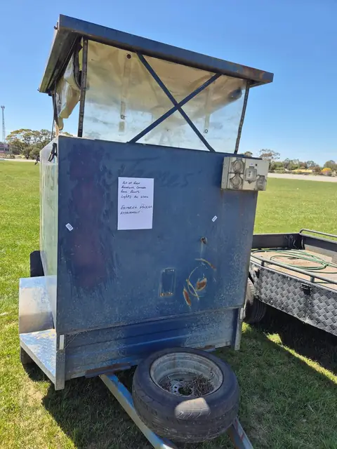 An enclosed box trailer with its lid propped open and a handwritten description taped to the side.